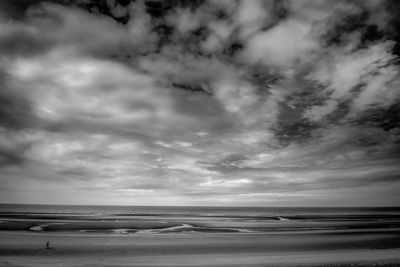 Scenic view of beach against cloudy sky