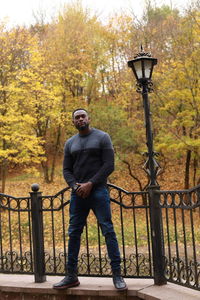 Portrait of man standing by railing during autumn