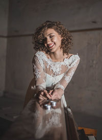 Happy young woman in wedding dress leaning on piano at home