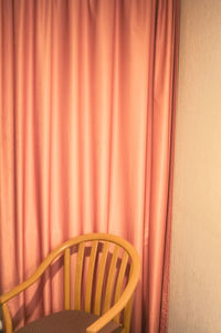 Empty chair against curtain