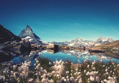 Scenic view of lake and snowcapped mountains against blue sky