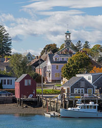 Houses at waterfront against cloudy sky