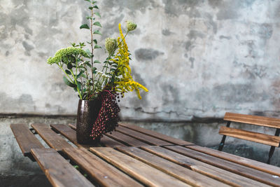 Plants in vase on wooden table against wall