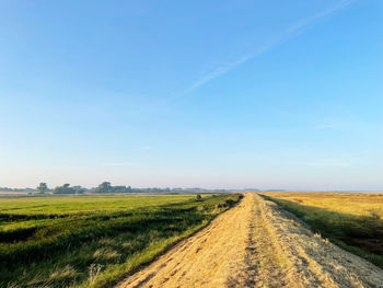 Road amidst field against sky