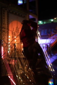 Young woman against illuminated lights at night