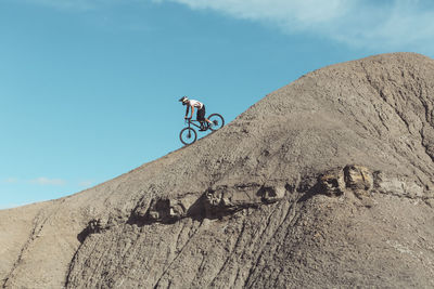 Side view of mountainbiker riding steep desert terrain