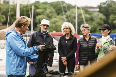 Male instructor explaining senior man and women about life jacket during boat master course