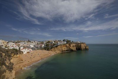 Scenic view of sea by townscape against sky