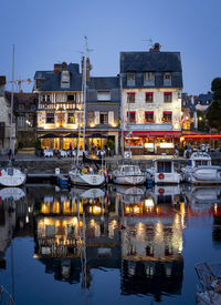 Boats moored in river by buildings against sky in city