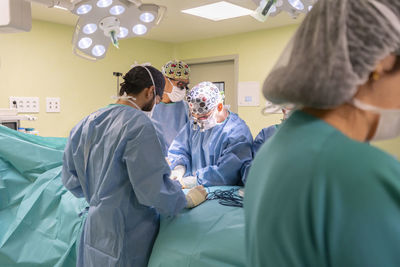 Surgeons and nurses performing surgery on patient in operating room