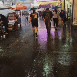 People walking on wet road in city