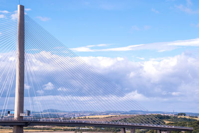 Low angle view of suspension bridge against cloudy sky