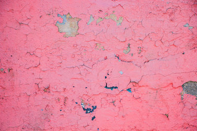 Cracks on a pink wall closeup