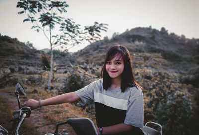 Portrait of smiling young woman with bicycle standing on mountain