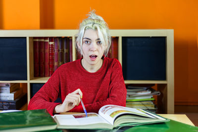 Portrait of young woman with mouth open studying in library