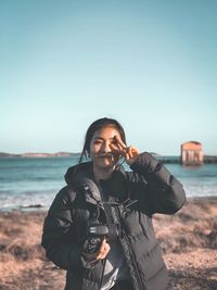 Portrait of woman standing on beach against clear sky