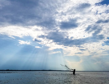 Silhouette of a fisherman in shallow sea water