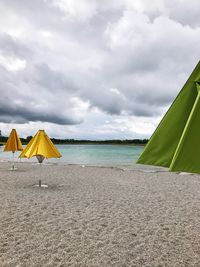 Deck chairs on beach against sky