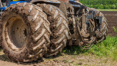Dirty double wheels of agriculture tractor on dirt road at sunny summer day