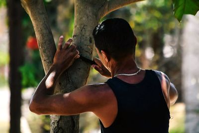 Midsection of man standing by tree in park