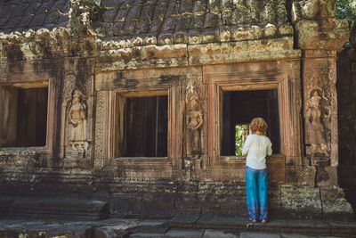 Rear view of mid adult woman standing outside ankor wat temple