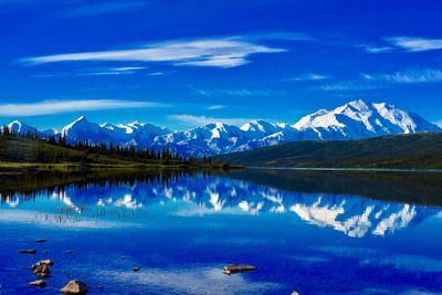 Scenic view of lake and mountains against blue sky