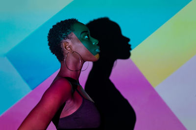 Side view of young woman standing against blue wall