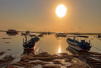 Fishing boats in sea at sunset
