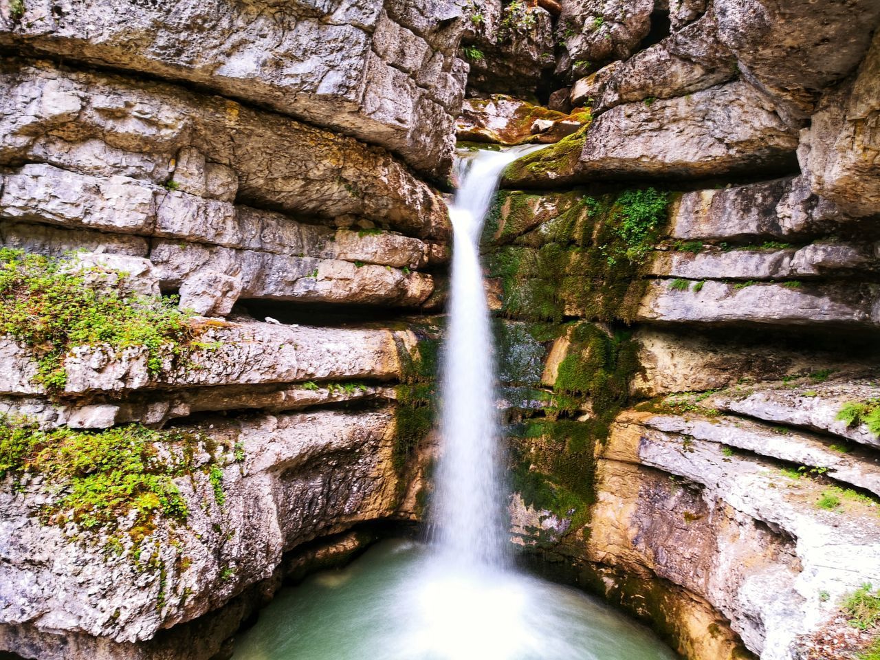 LOW ANGLE VIEW OF WATERFALL ON ROCK AGAINST TREES