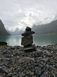 Stack on stones at lakeshore against sky