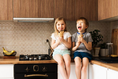 Siblings eating ice cream at home