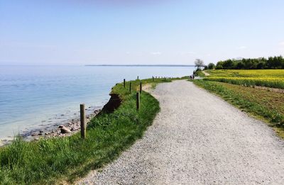 Scenic view of road by sea against sky