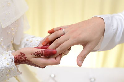 Cropped image of bride putting wedding ring on bridegroom finger
