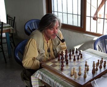 Senior man smoking pipe while playing chess at home