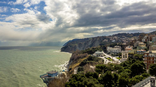 Scenic view of residential district and sea against cloudy sky