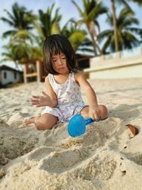 Full length of girl playing with sand at beach