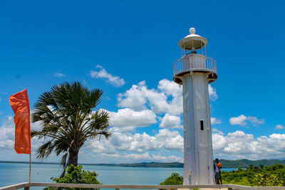 Lighthouse by sea against blue sky