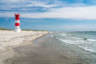 Lighthouse on beach against sky