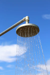 Low angle view of water drops against blue sky