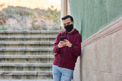 Full length of young man standing on mobile phone