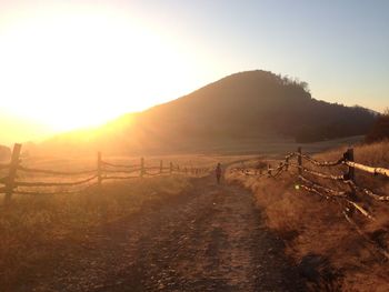 Dirt road along landscape at sunset