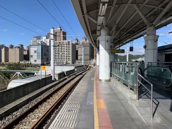 Railroad station platform in city against sky