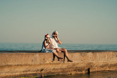 Dad and daughter in santa claus hats eat ice cream on the pier