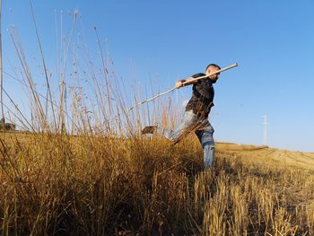 Full length of man running on field against blue sky