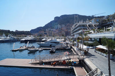 Sailboats moored in sea against buildings in city