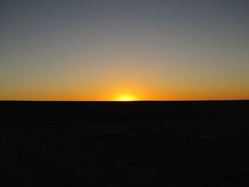 Scenic view of desert against clear sky during sunset