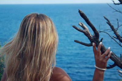 Close-up of woman hand holding sea against sky