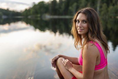 Smiling woman sitting at lake