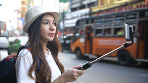 Portrait of young woman using mobile phone in city