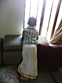 Rear view of boy on sofa at home